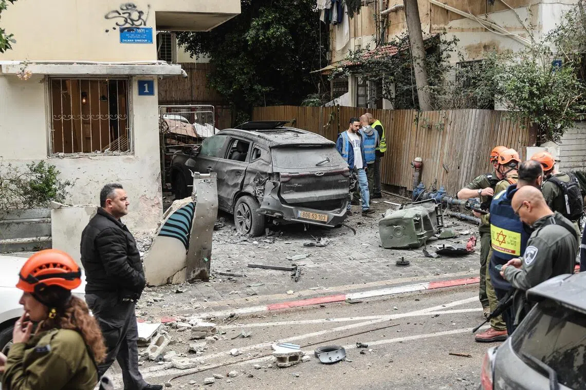 以色列誓言将粉碎伊朗政权，图为以色列特拉维夫一处住宅区星期三遭伊朗导弹袭击后，安全部队与急救人员在现场展开工作。（法新社）