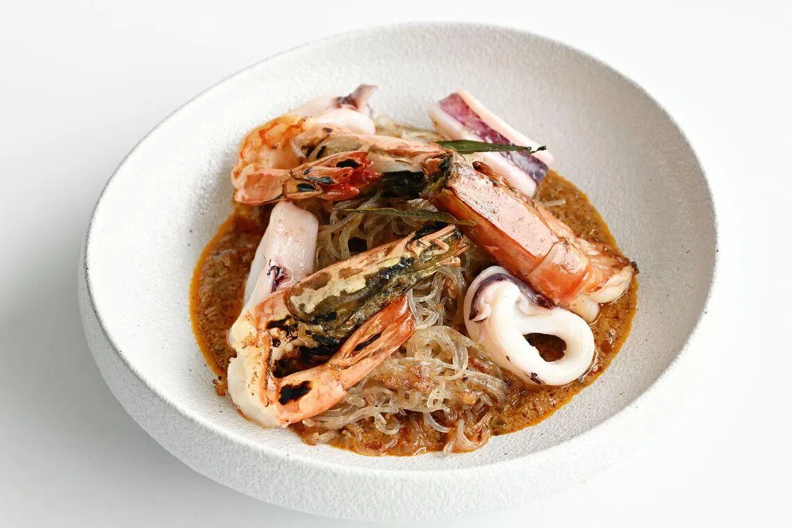 海鲜干叻沙的粉条充分吸收叻沙酱汁，还有烤虎虾和墨鱼添香。（餐馆提供）