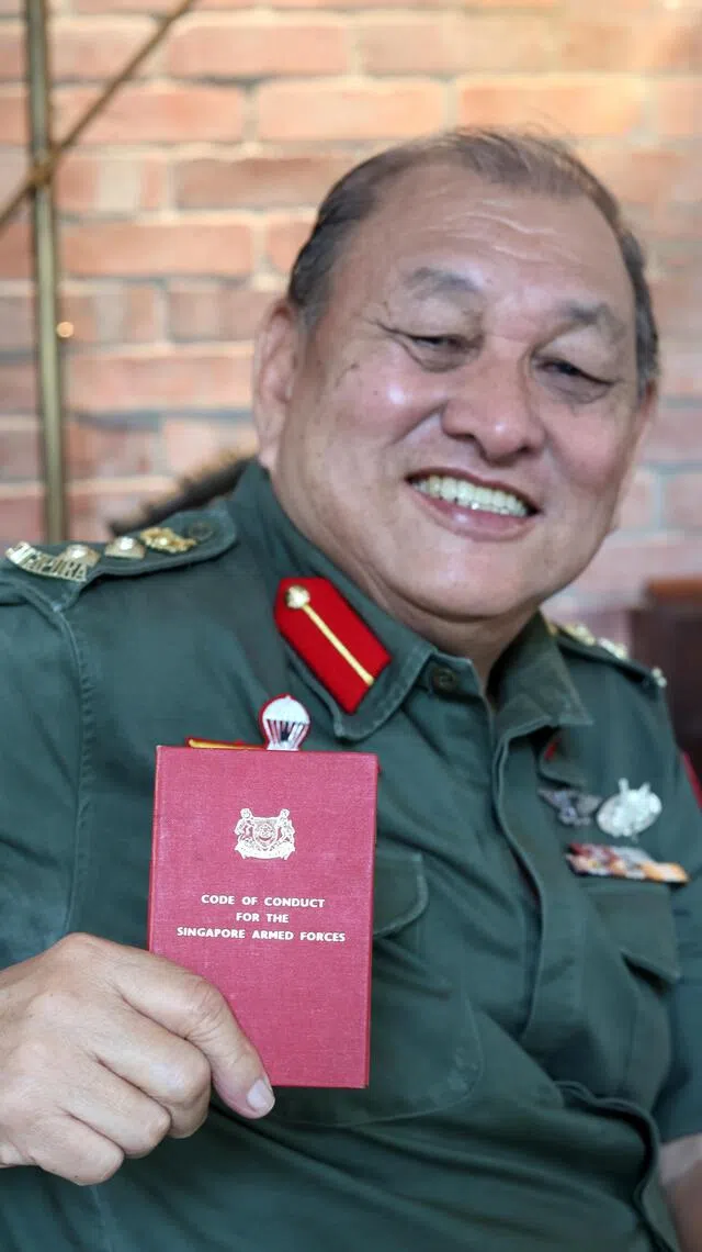 退休20多年，林耀平这本写着新加坡武装部队行为守则的小红册仍保留完整。（龙国雄摄）
