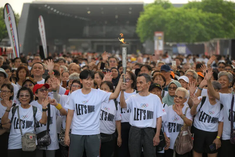 久违的我国乒乓球国手周靖祎高举奥林匹克火炬，带领约2000人展开环绕加冷汇，约3.7公里的奥林匹克步行活动。（海峡时报）
