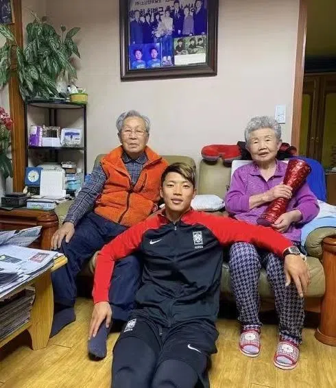 韩国球星黄喜灿（中）与从小抚养他长大的爷爷奶奶合影。（互联网）
