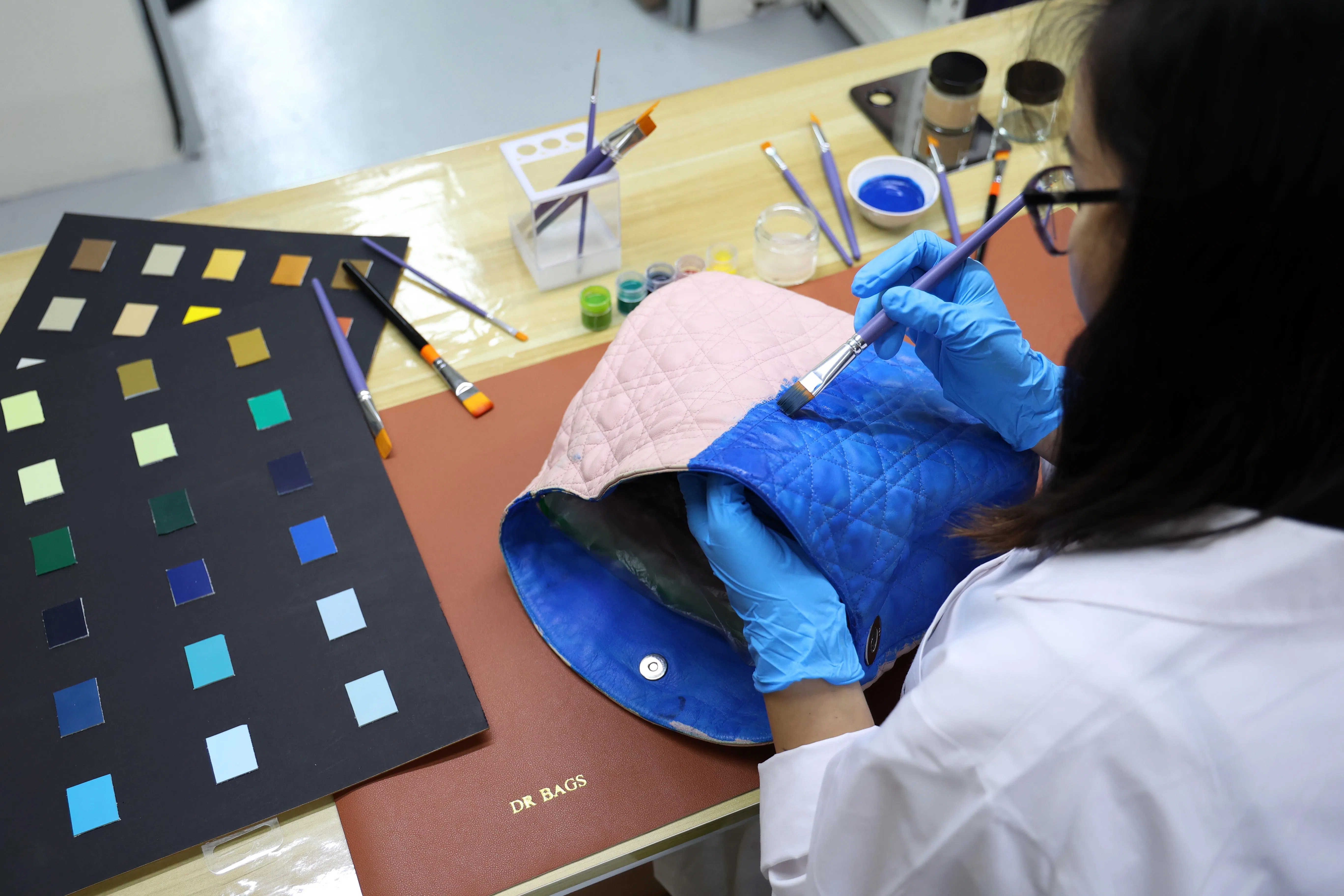 包包博士为顾客的旧皮包漆上新色，再用烘干机吹干，旧包顿成新包。（林明顺摄）