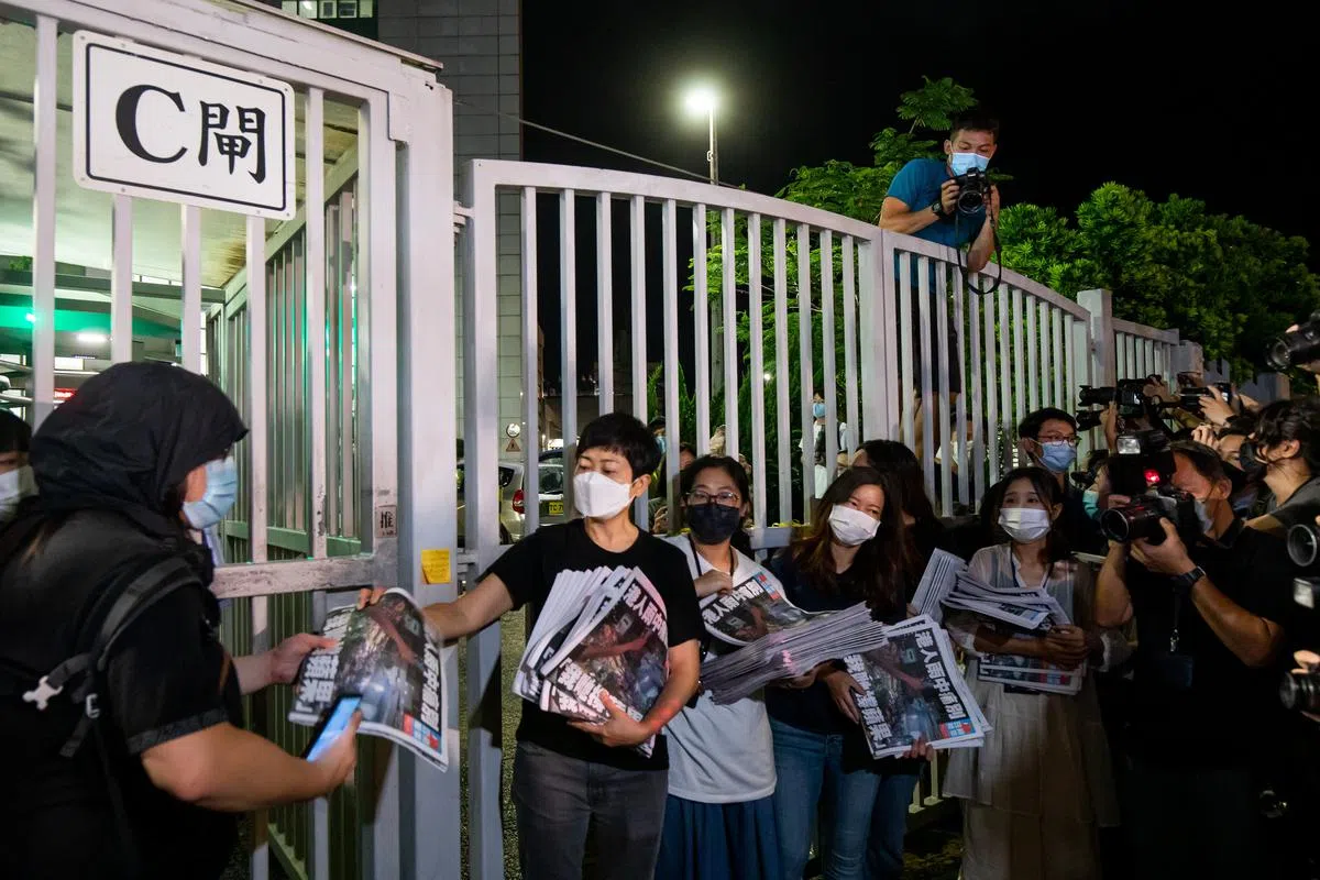 香港《苹果日报》员工今天凌晨在办公大楼外分发最后一期的《苹果日报》。（彭博社）