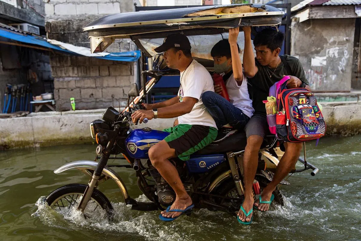 哈戈诺伊镇的电单车德士司机用钢管“加长”前叉管和后叉，以架高车身，避开底下积水。（路透社）