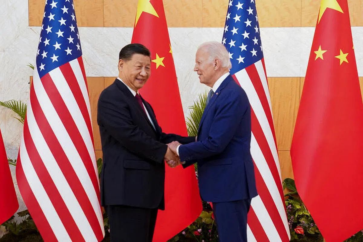 拜登（右）以双手与习近平握手示意，习近平则用左手搭拜登的手臂。（路透社）