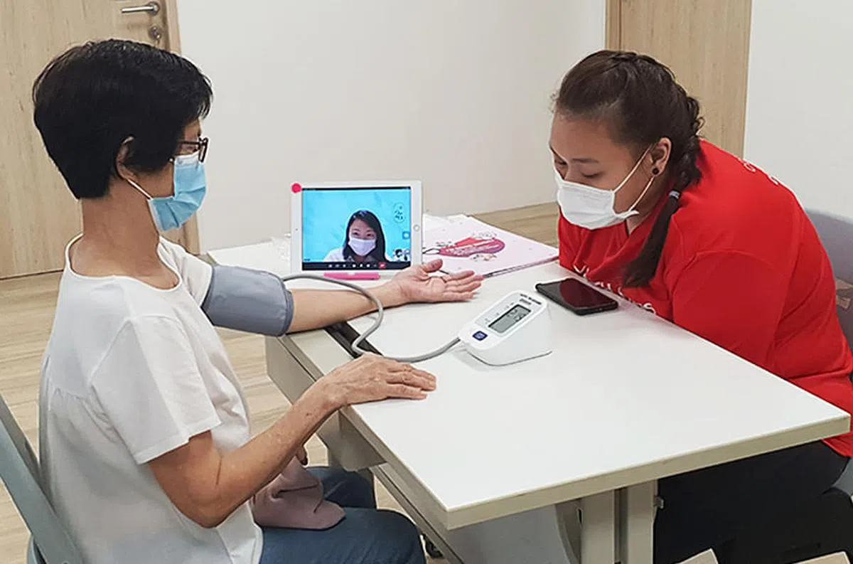 乐龄在飞跃义工的陪同下学会自己量血压和体重等，并且通过视讯进行看诊。（图／资讯通信媒体发展局）