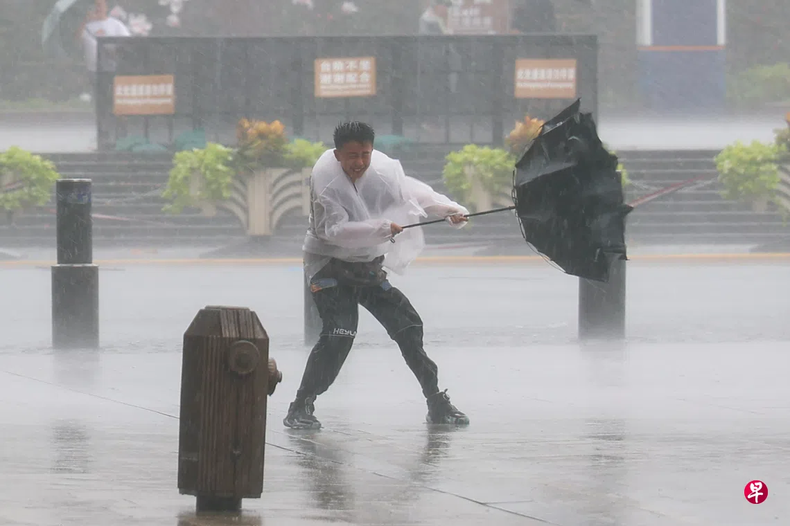 台风“白海豚”8月9日登陆中国浙江省，给华东地区带来暴雨。图为一名行人在上海黄浦区南京东路上，用力抓住被风吹开的雨伞。 （新华社）
