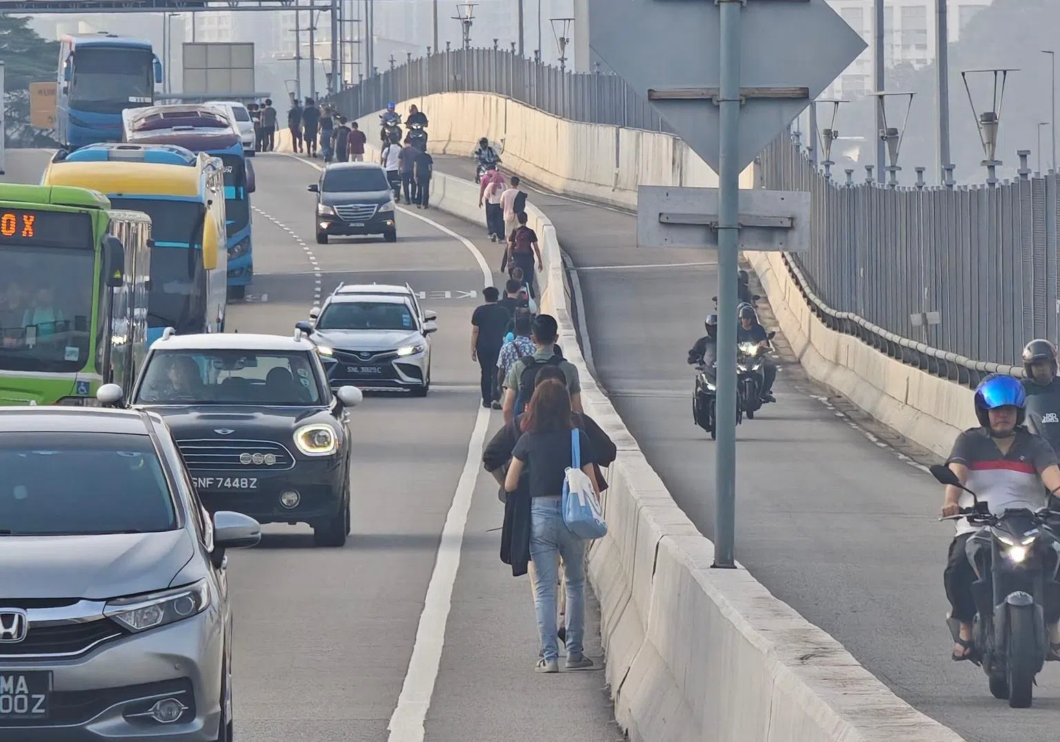 在靠近新山关卡一侧，由于没有人行道，步行越堤的通勤者只能走在马路上。（取自脸书）