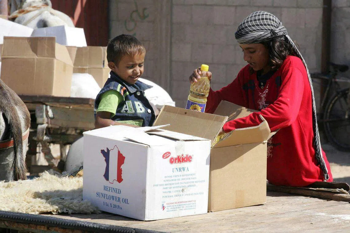 加沙地带交战双方若达成协议，救援物资将能运至加沙所有地区长期靠联合国口粮度日的巴勒斯坦人。照片为2008年10月16日，巴勒斯坦儿童在加沙南部拉法难民营打包联合国近东巴勒斯坦难民救济和工程处（UNRWA）分发的粮食。（法新社）