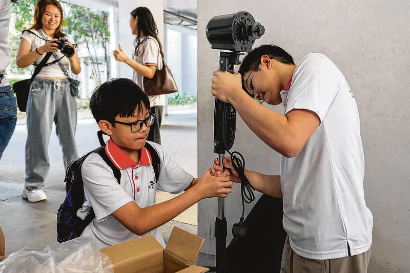 谭辉问和另一名义工一起把风扇组装好。