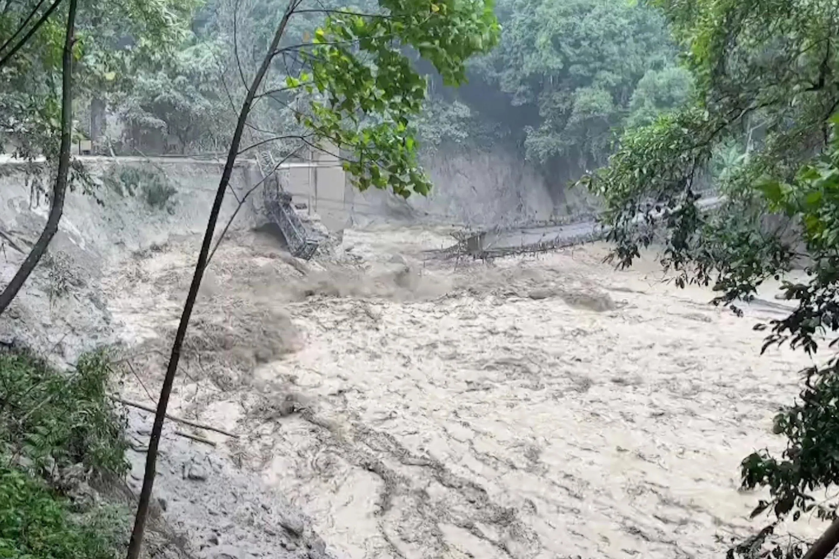 印度军方星期四公布的视频画面显示，洪水已将提斯塔河（Teesta River）上方的桥梁冲垮。（法新社）