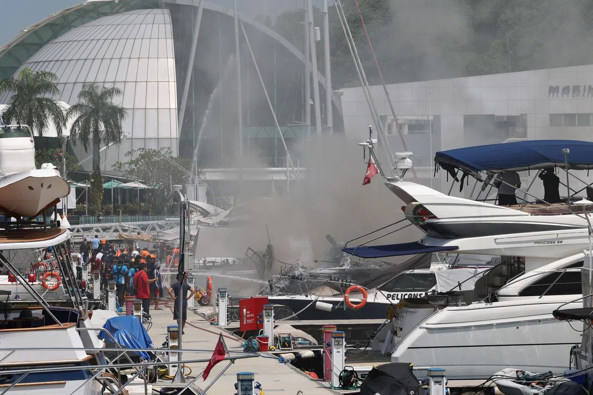 数名民防人员在进行救火行动，游艇仍冒出浓浓黑烟。（张思庆摄）