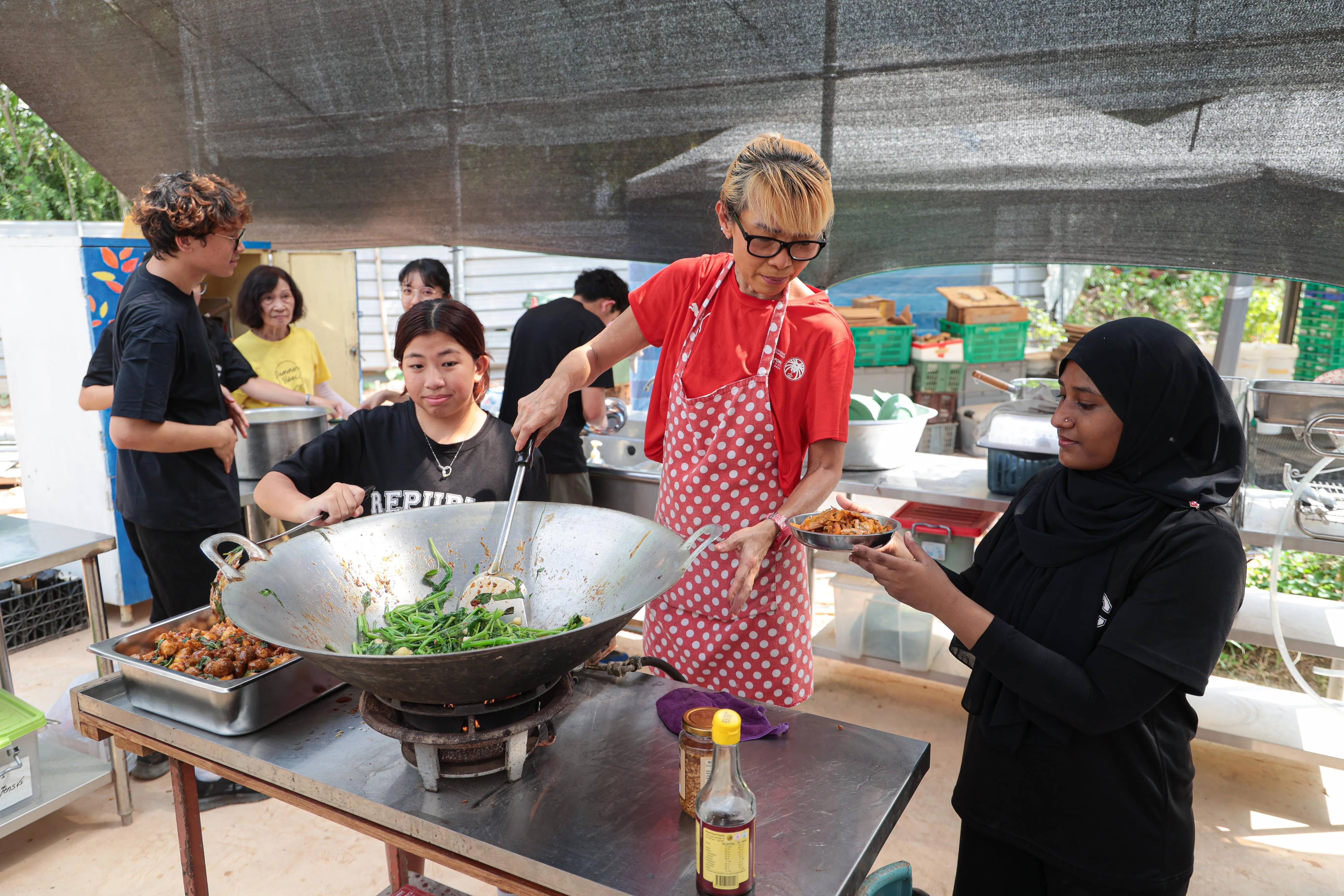 张海燕（红衣）是义工最喜欢的大厨，她每个月来做饭的那个星期六，是大家最期待的一天。（李冠卫摄）
