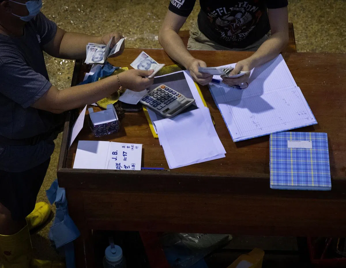 鱼商贩向顾客收取现金，并记在账本上。（陈来福摄）