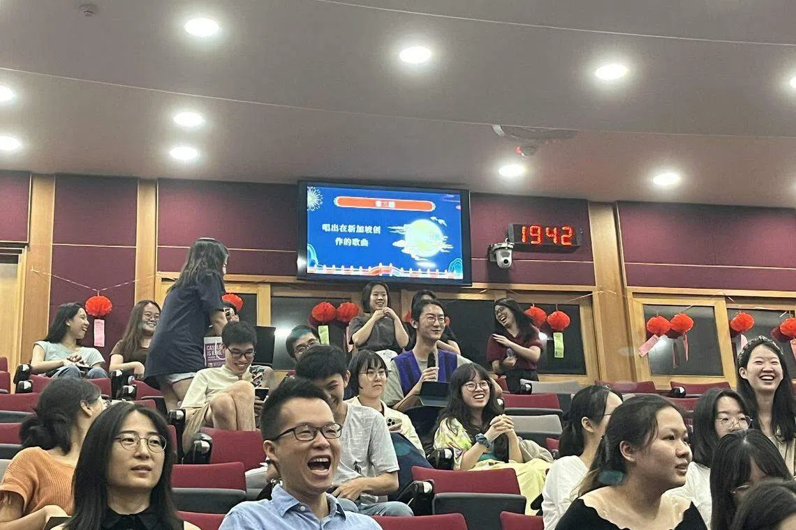 “知音识曲”游戏中，大家都毫不害羞地抢麦克风，积极参与，一片欢声笑语。（国大中文系提供）