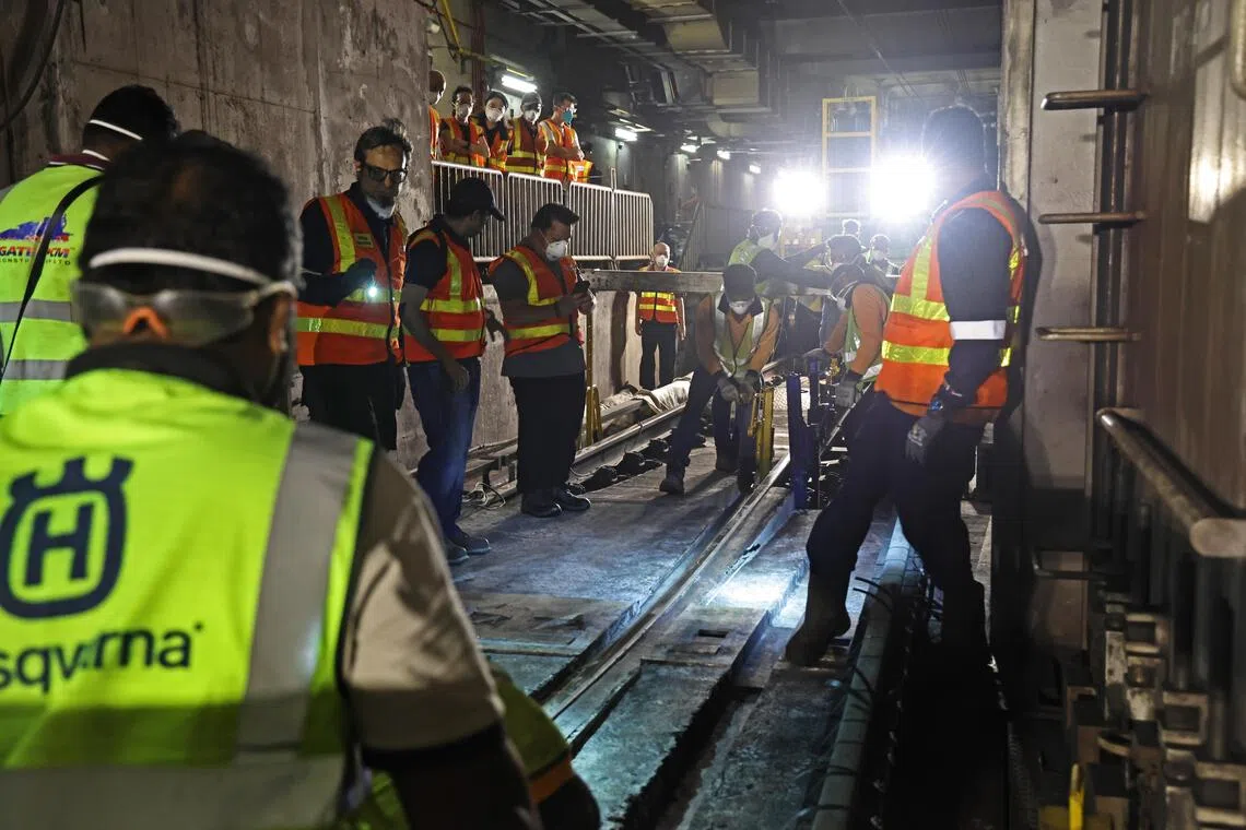 工程人员在切割完毕后，将旧铁轨从隧道基座中取出，为安放新轨道作准备。（陈渊庄摄）