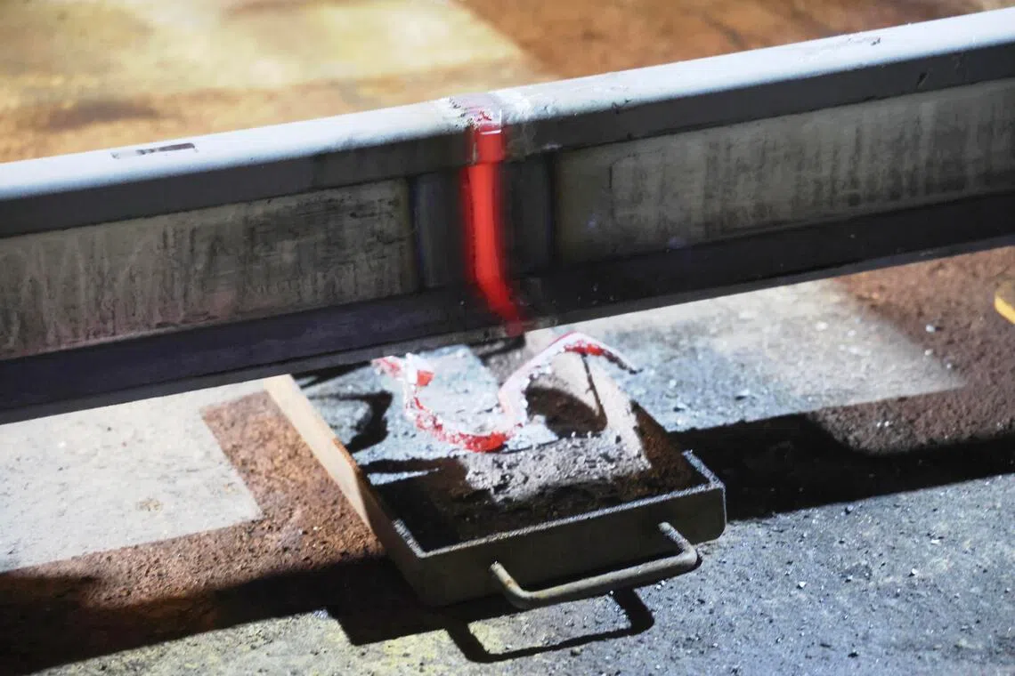 闪光对焊机操作过程中，钢轨在电流与压力作用下被压合成形，高温金属发红后迅速融合成一体，冷却后形成平整焊缝。（郑一鸣摄）