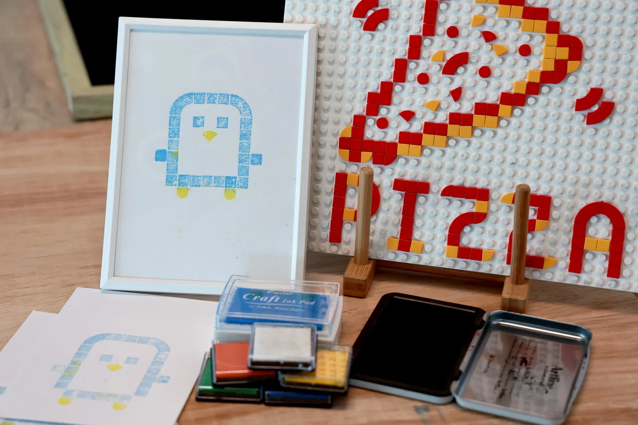 胡振辉让小朋友用乐高砖块制作印章，在环保纸上盖章。（龙国雄摄）