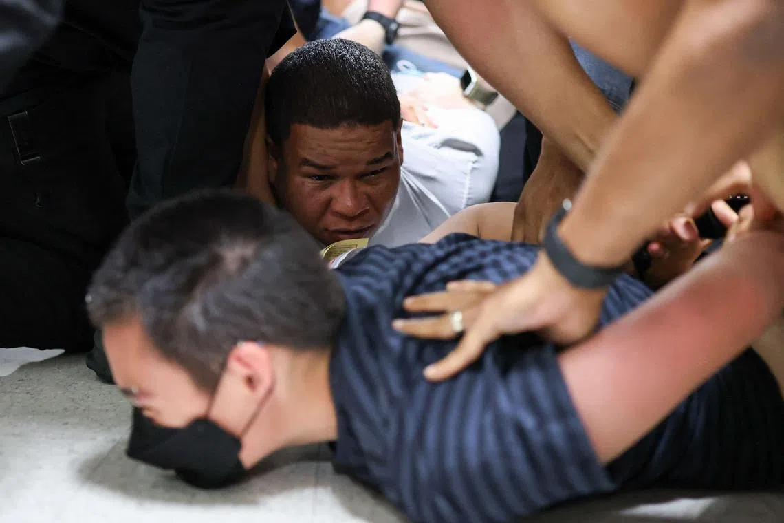 美国便衣联邦执法人员在纽约法院走廊突袭两名移民，将他们按倒在地，上铐带走。（法新社）