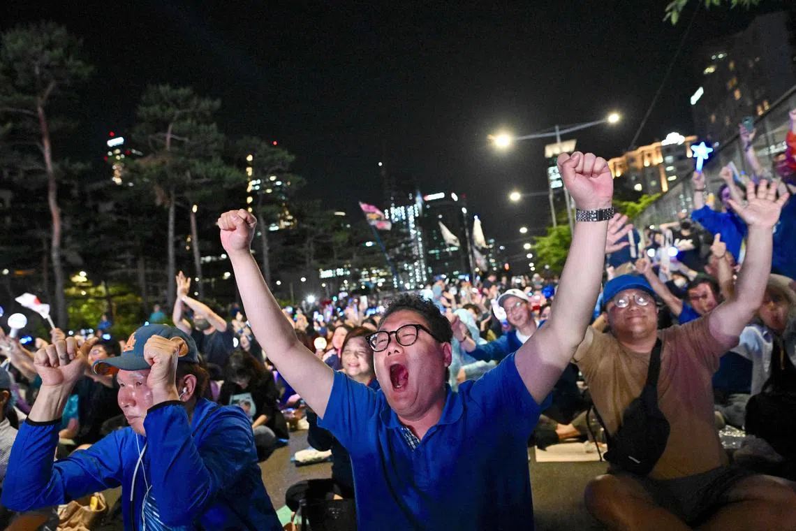 出口民调显示李在明大幅度领先后，在首尔市街头聚集的李在明支持者兴奋欢呼。（法新社）