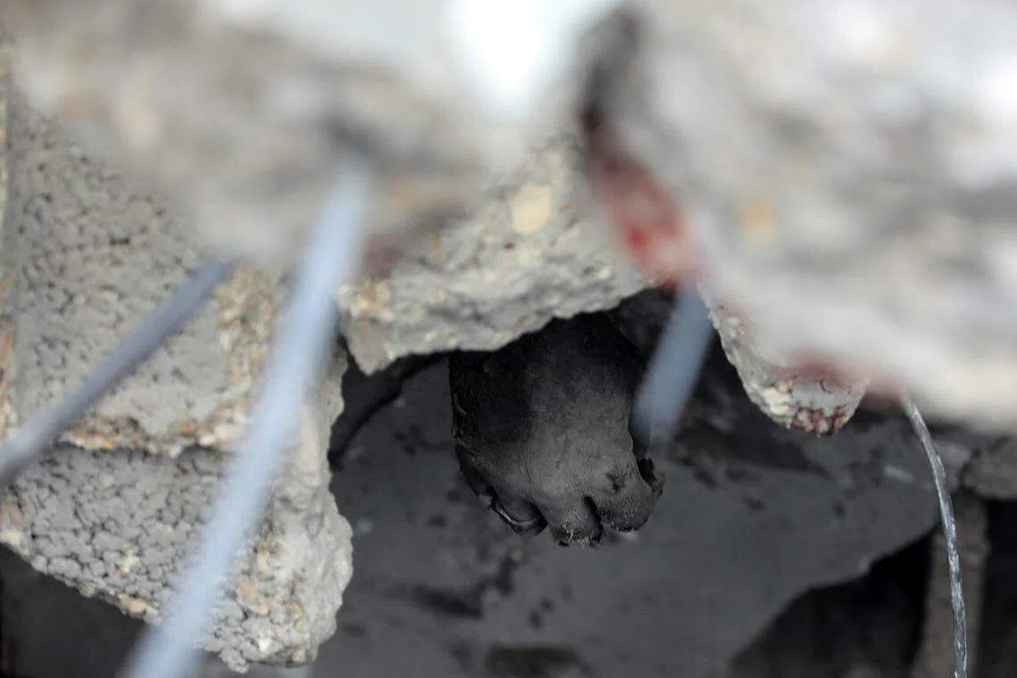 7月9日，加沙中部的努赛拉特难民营遭袭后，一名丧命的巴勒斯坦人被压在倒塌的废墟中。（路透社）