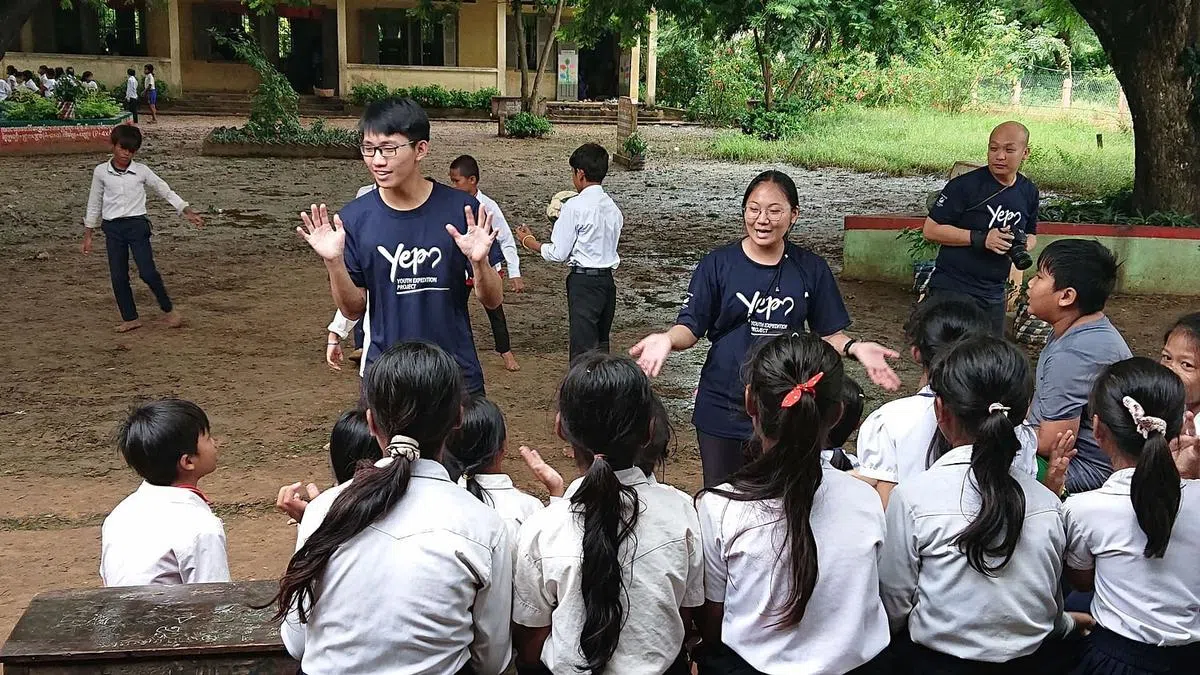 李明光（左一）在室外为当地学生授课。（全国青年理事会提供）