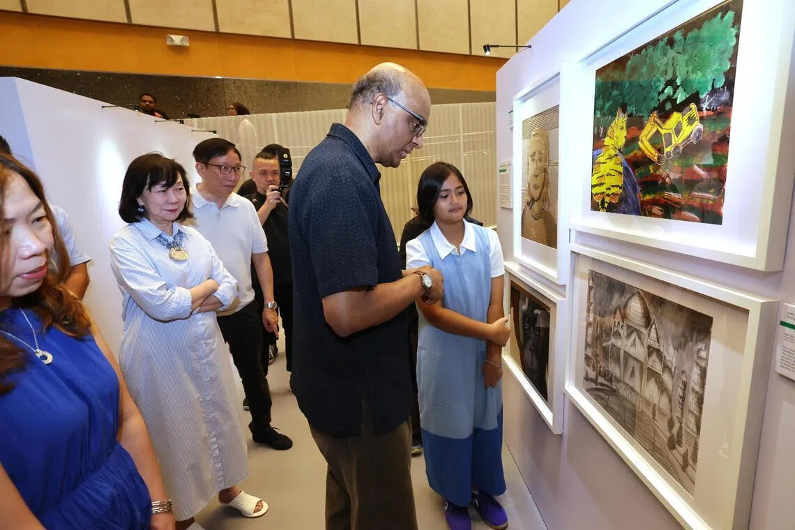 总统尚达曼星期六（4月4日）上午为艺术展主持开幕仪式。他在艺术展上欣赏爱美丽（总统左边）的作品。（梁麒麟摄）