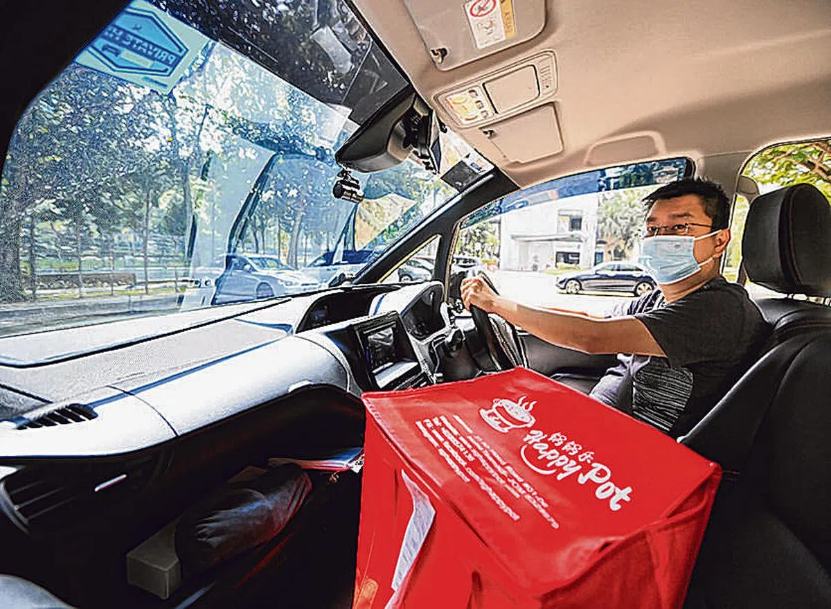刘祖蔚年初和朋友合开一家火锅店，他一边做grab司机，一边安排送货。（龙国雄摄影）