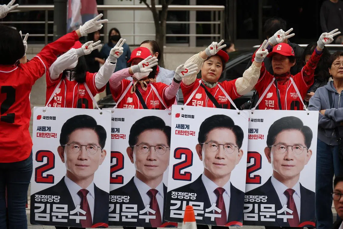 国民力量党总统候选人金文洙的支持者星期一（5月19日）在首尔中部齐聚，拿着他的巨大海报，为竞选活动造势。（路透社）