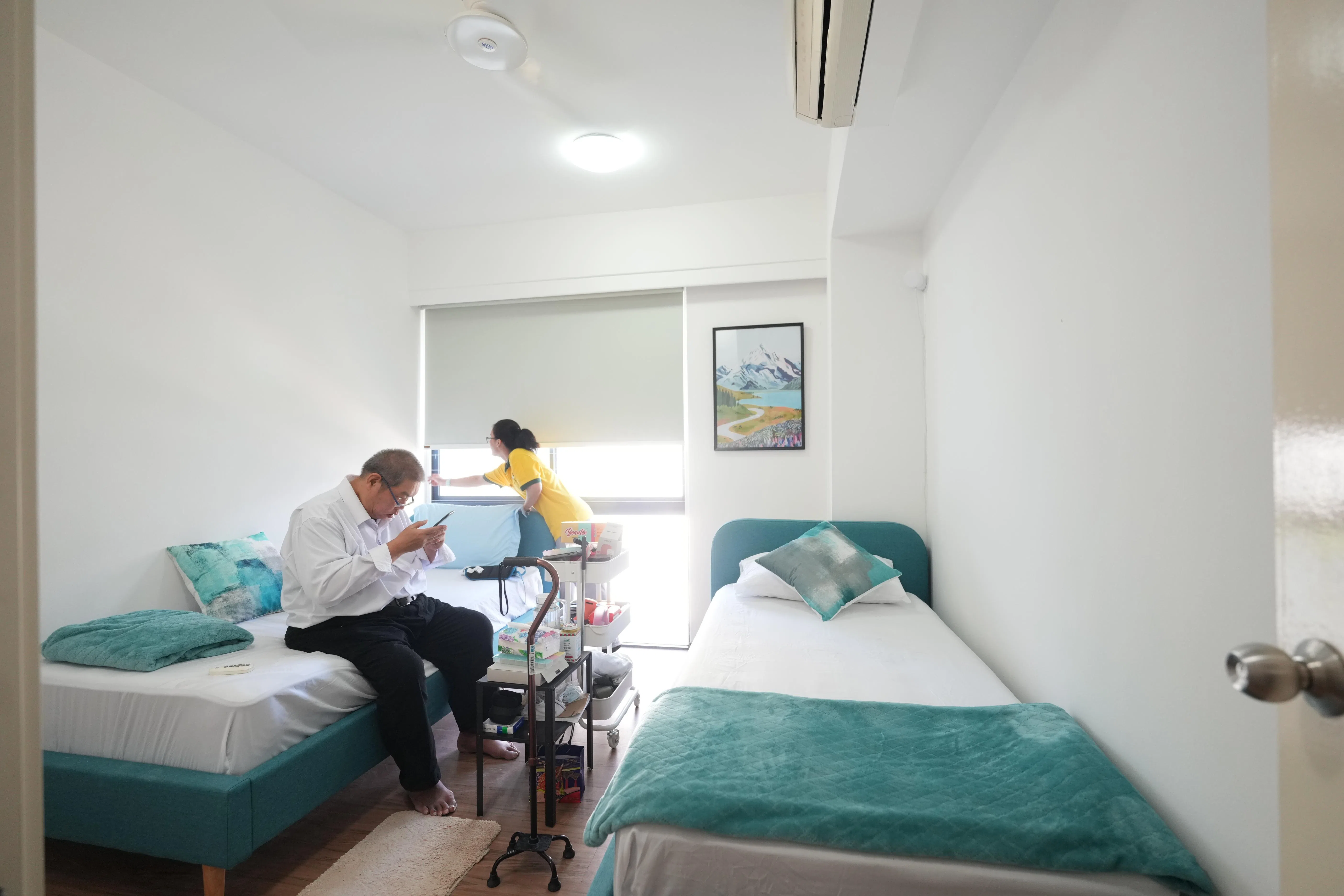 
叶中英（左）上个月搬进淡马锡理工学院的生活辅助村，有看护照料。生活辅助村使用学院住宿楼的其中几个单位。每个单位有客厅、三个房间和厨房、叶中英住的是双人房。（谢智扬摄）