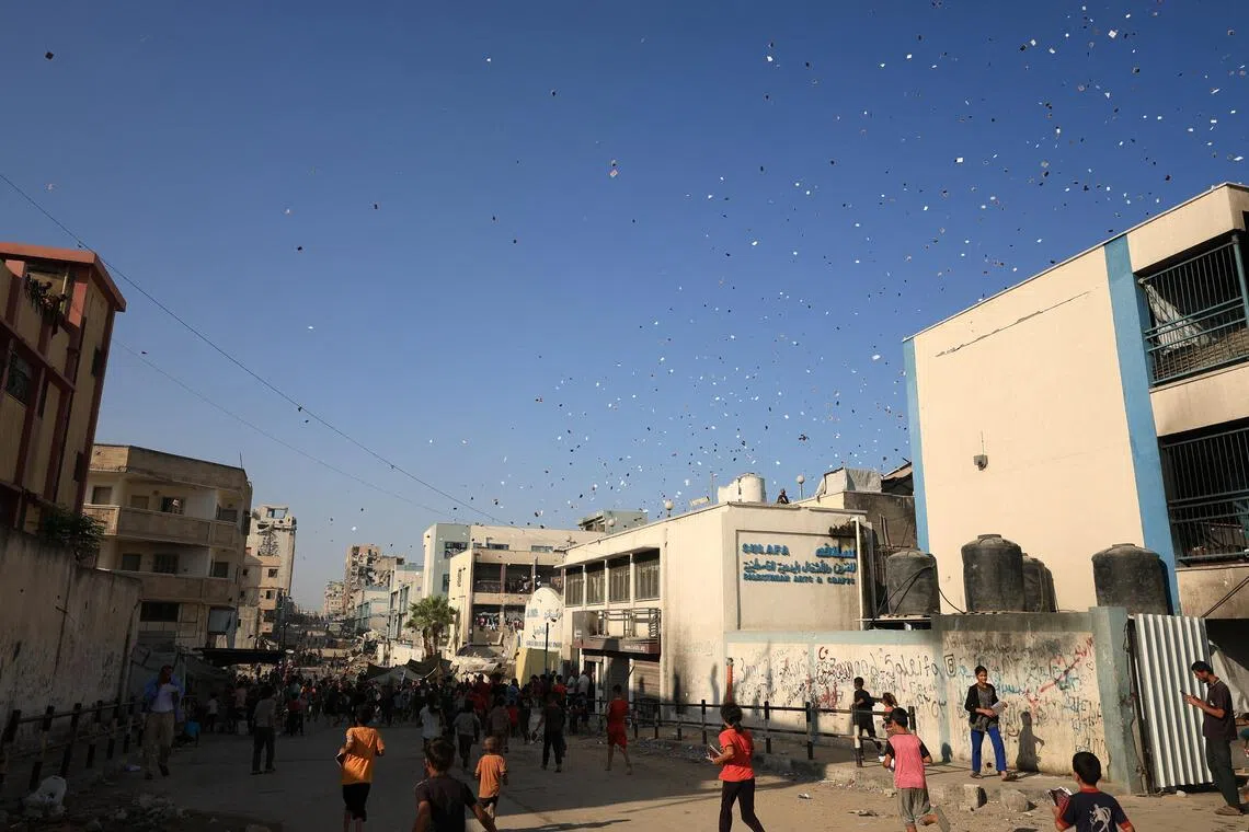 9月17日，巴勒斯坦人奔跑收集以军在加沙城投放的传单，要求当地居民立即撤离。（路透社）