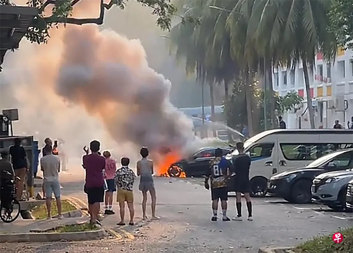 汽车起火，引擎舱遭烈火吞噬，不少公众站在远处围观。 （TikTok视频截图）