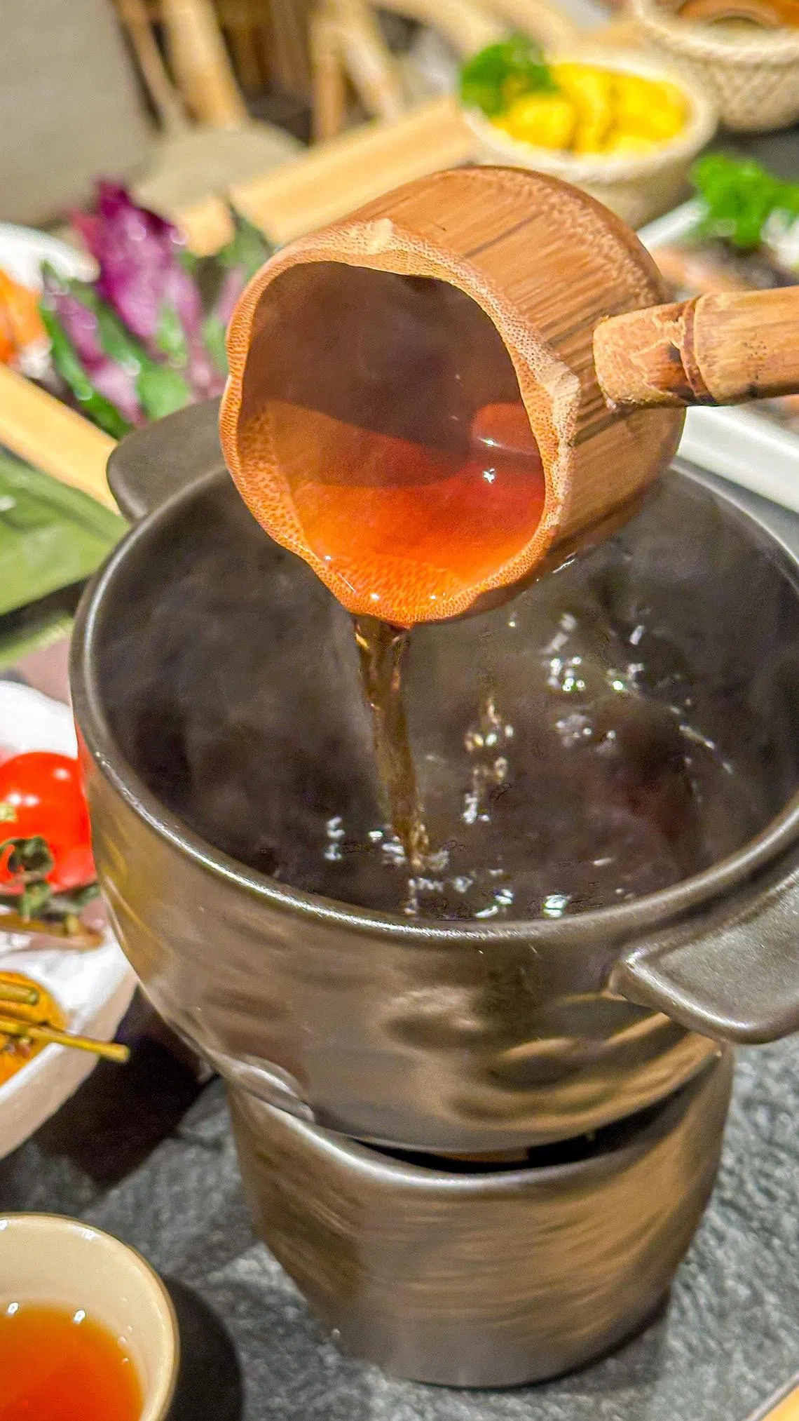 从陶壶缓缓舀出热茶倒入茶杯，店家希望食客放慢脚步享受火锅。（餐馆提供）