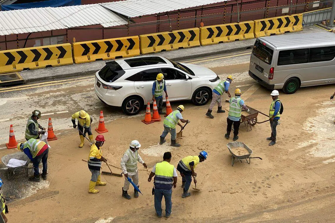 陆交局承包商工人用铁锹和推车清理路面淤泥。（邝启聪摄）