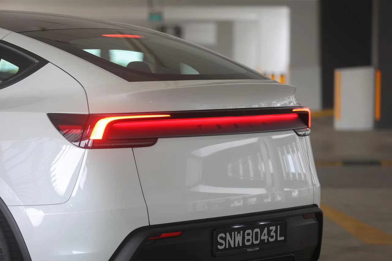 红色尾灯投射在有特斯拉英文名的车体上，营造出独特视觉效果。（陈心媛摄）