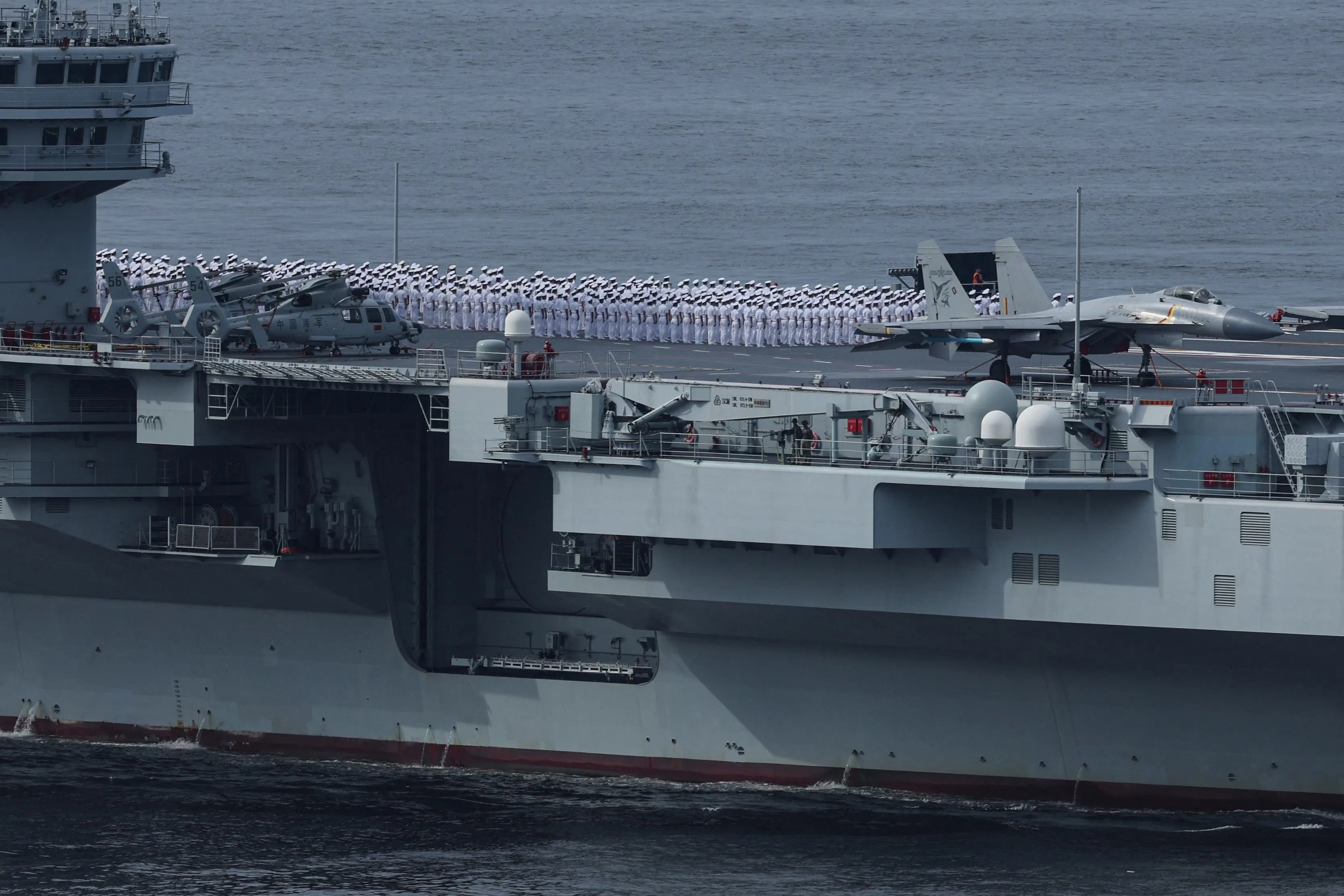 海军水兵在山东舰甲板上列队，在一旁的是歼-15战机。（路透社）