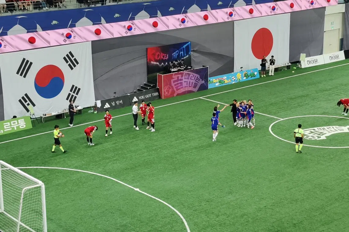 日本球员（蓝衣）赛后庆祝胜利，韩国球员（红衣）则显得失落。（陈明耀摄）