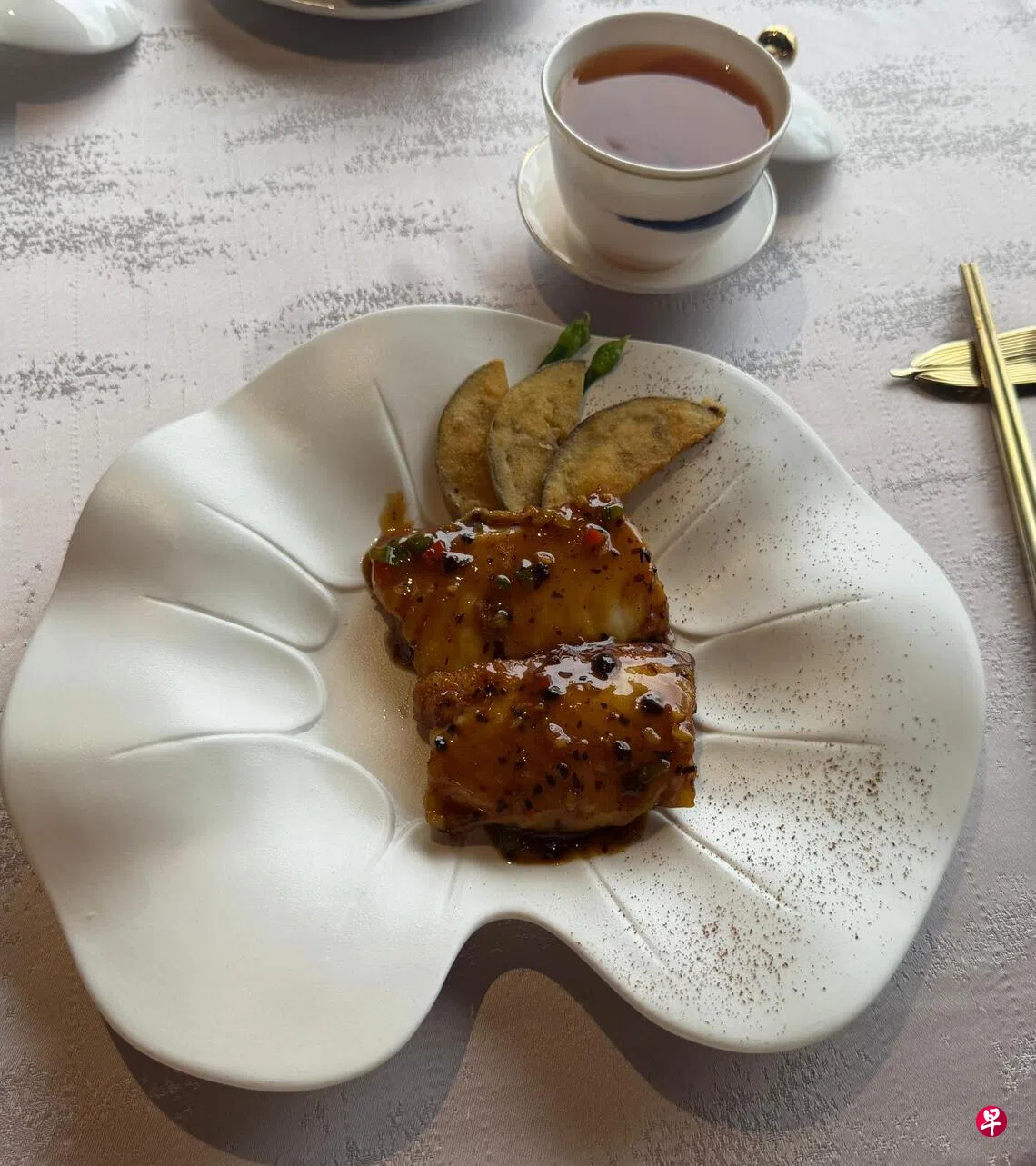 远年陈皮豉蒜煎酿斑件，摆盘有心思，一边是鱼片，一边放上25年陈皮粉，可以选择原味或蘸陈皮粉，体验不一样的风味。 （作者提供）