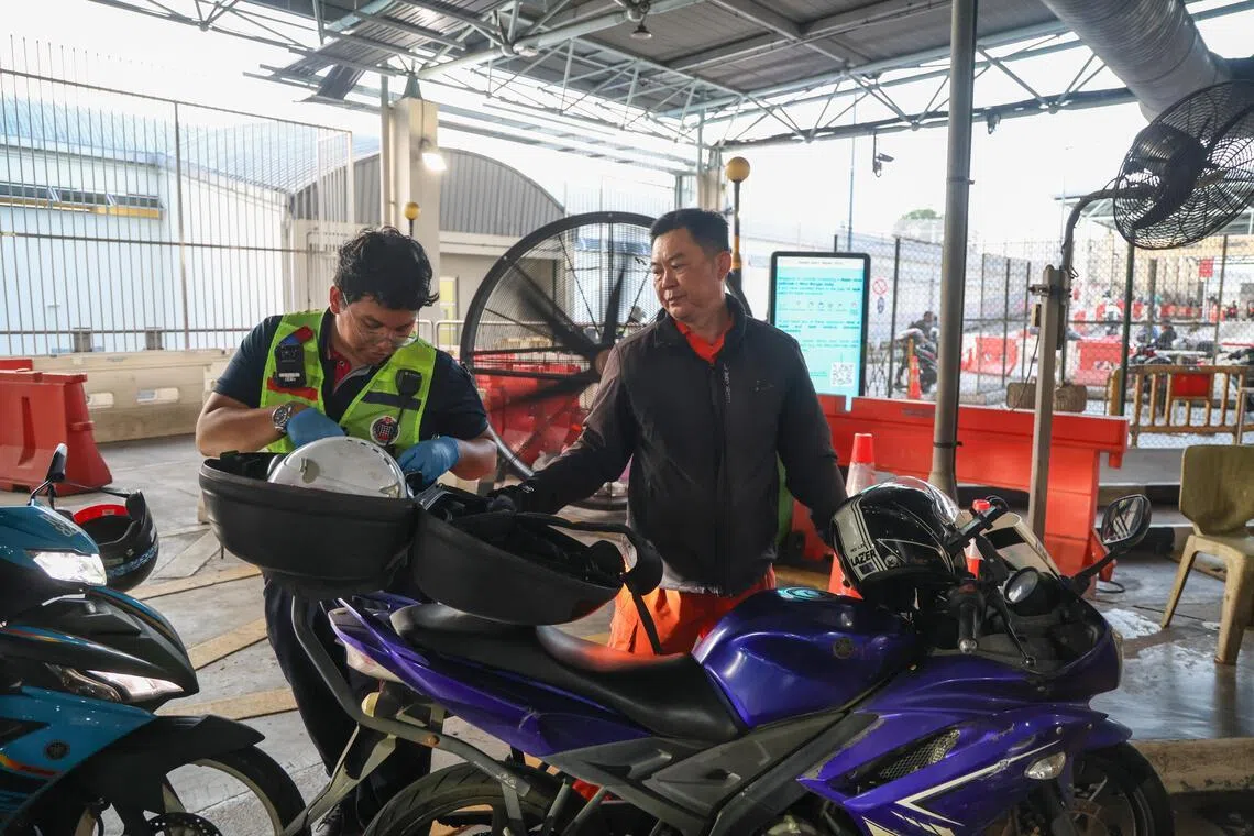 如果电单车后备箱内放置背包或其他物品，执法人员会翻包检查，确保没有违禁或可疑物品入境。（白艳琳摄）