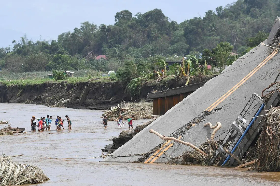 10月25日的照片显示，热带风暴“潭美”给八打雁省劳雷尔带来暴雨，洪水冲毁桥梁，人们只能从桥边渡河。（法新社）
