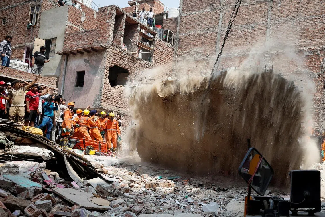 4月19日，印度新德里一楼楼房倒塌，紧急救援人员使用起重机拆除废墟上的一块楼板。（路透社）