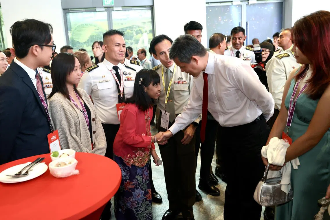 公共服务统筹部长兼国防部长陈振声（右二）在国庆庆典答谢活动上，与庆典滨海湾庆祝活动演出者，11岁的小提琴手郭淑琴握手寒暄。（陈斌勤摄）