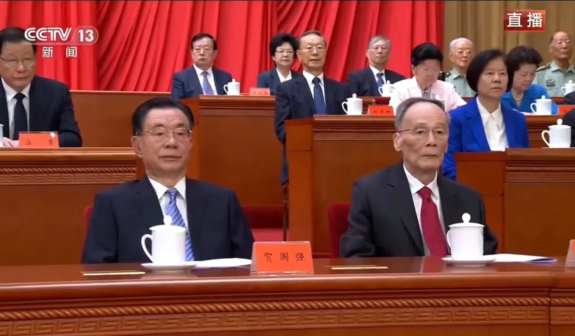 星期一上午，多名中共退休领导人在北京人民大会堂出席纪念江泽民诞辰100周年大会，据央视新闻画面，出席大会的中共元老包括中共中央前纪委书记贺国强（前排左）、中国前国家副主席王岐山（前排右）。（央视直播视频截图）