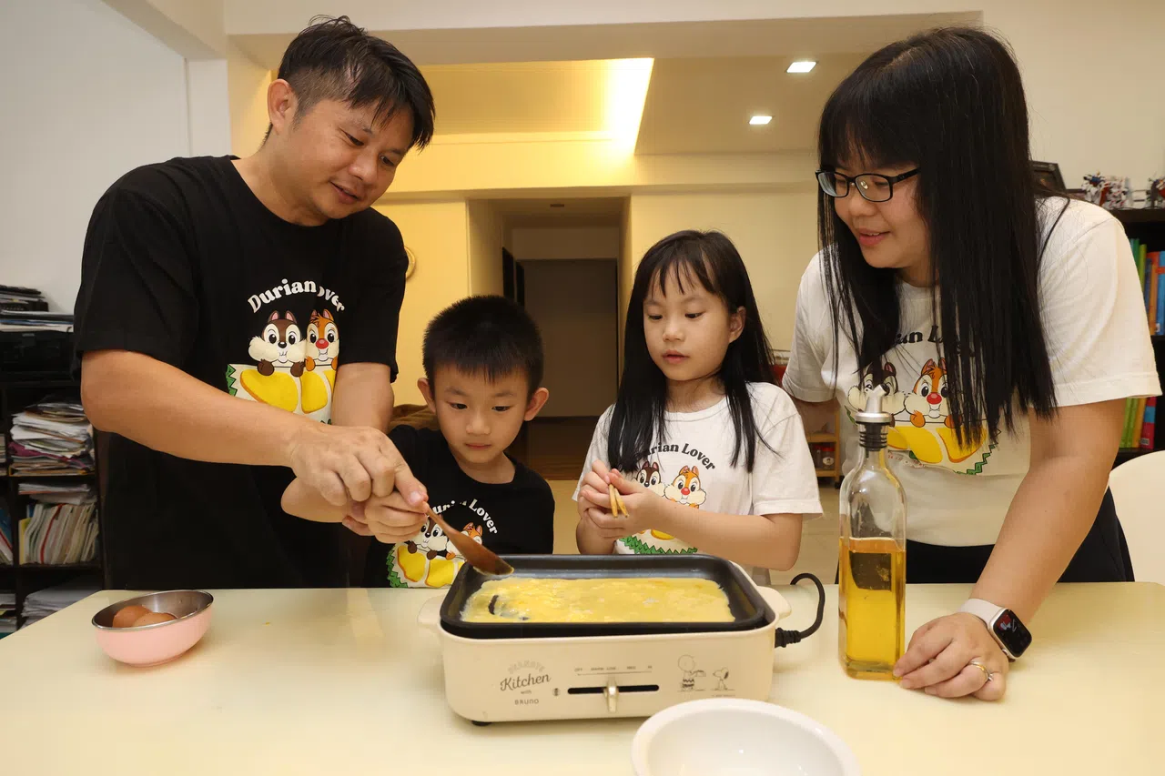 俞书信（左一）手把手教导儿子聿宣（左一）和女儿聿勋（左三）煎蛋；妈妈戴景婷在旁监督。（唐家鸿摄）