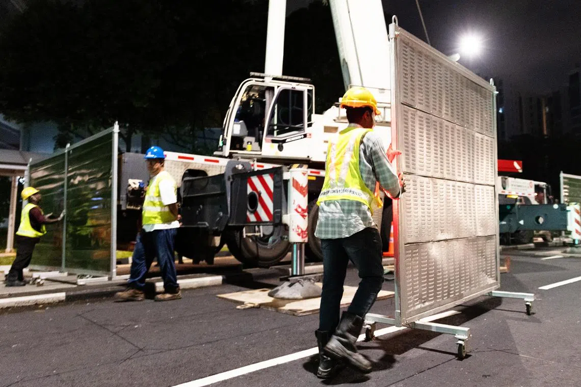 工人推动隔音屏板，摆在250公吨起重机周围，以减少起重机发动机的噪音。（蔡家增摄）