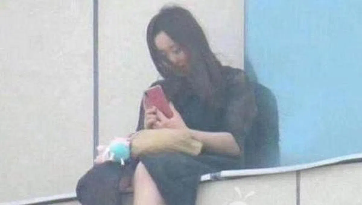 2018年6月20日，甘肃庆阳西峰区一名19岁女孩李某坐在商场八楼窗台，犹豫是否要自杀。（互联网）