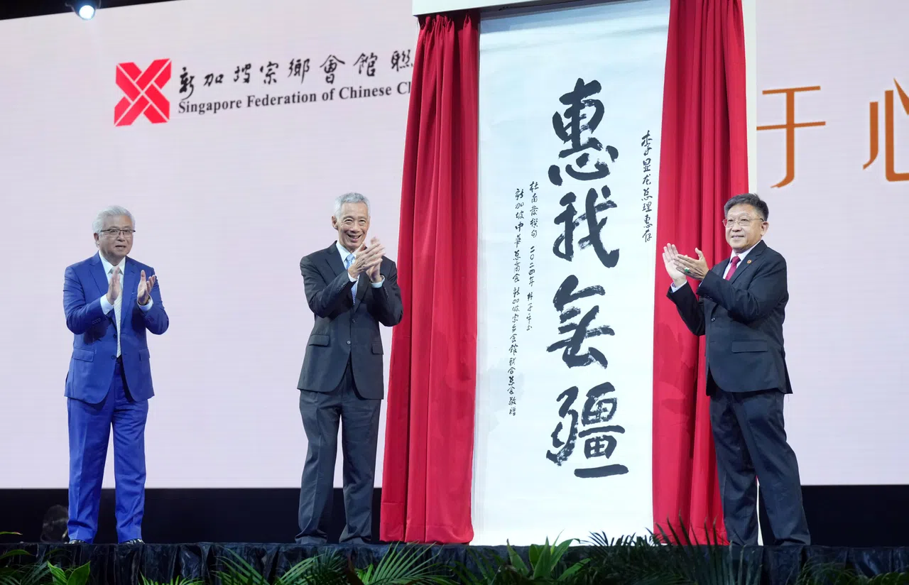 新加坡宗乡会馆联合总会会长蔡其生（左）和新加坡中华总商会会长高泉庆（右）星期三晚上在向国务资政李显龙致敬的晚宴上，将103岁本地书画家林子平的书法“惠我无疆”赠送给李显龙。（谢智扬摄）