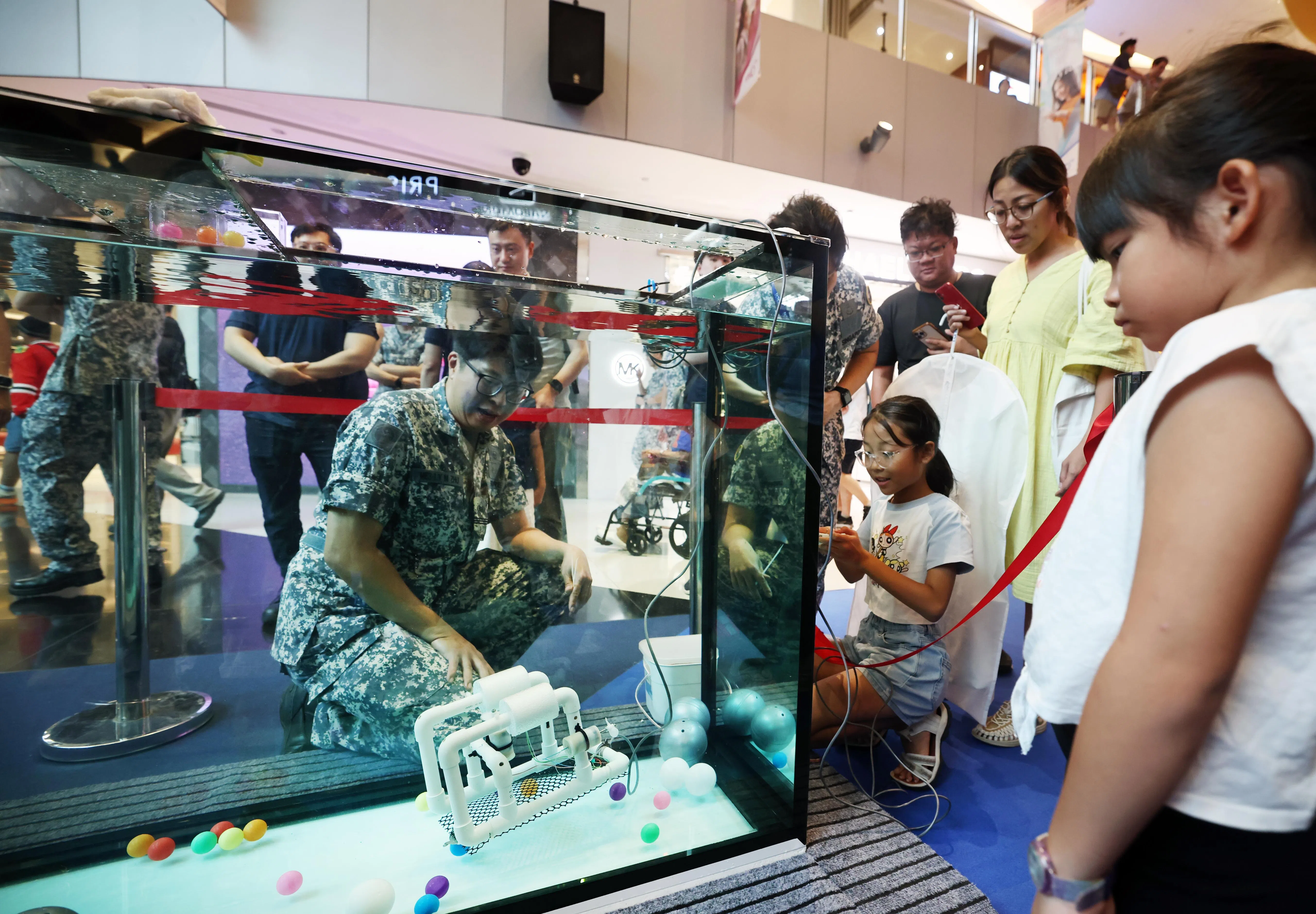 孩子们也可以操控SeaPerch遥控潜水器，将透明水缸中的彩色小球拾起。（陈渊庄摄）