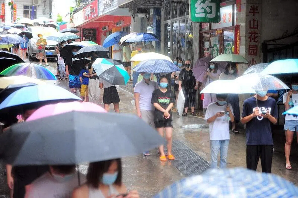 8月8日，海南省三亚市市民和旅客在大雨中排队等待进行核酸检测。（法新社） 