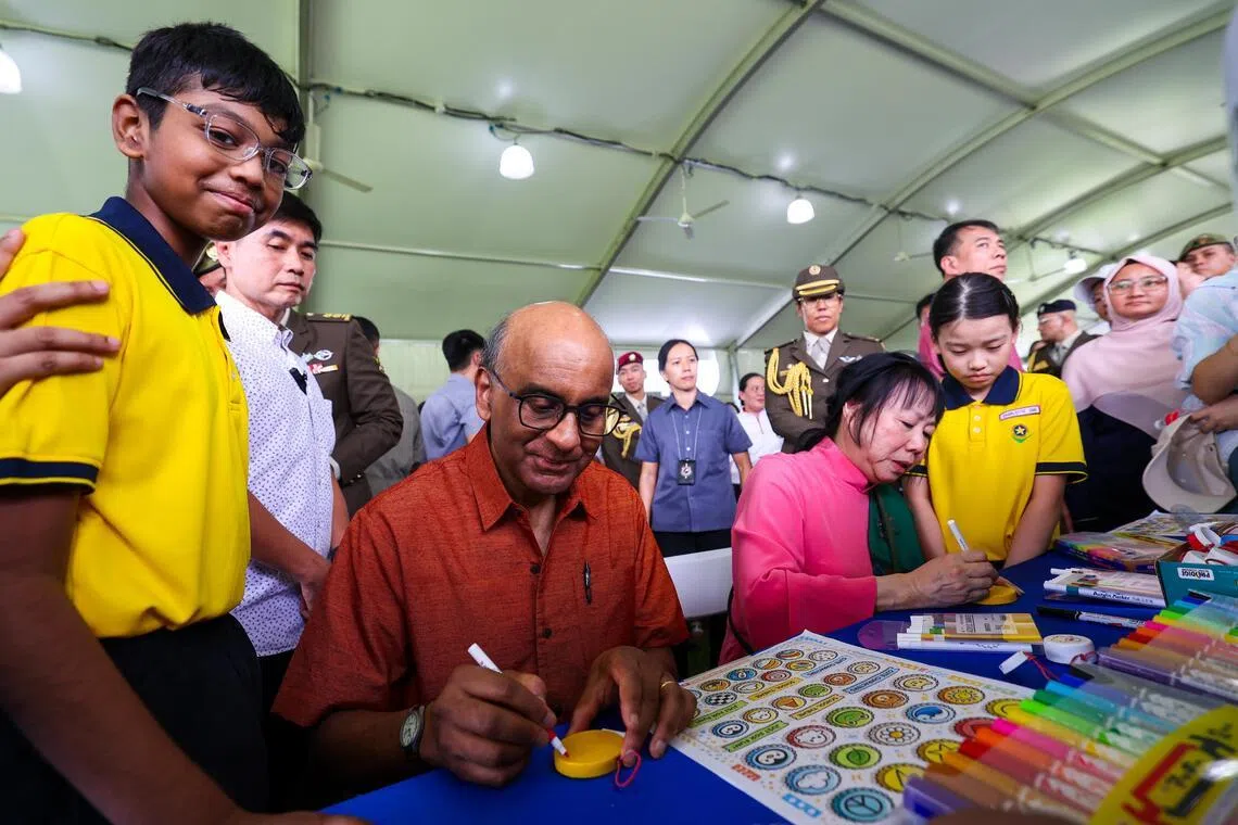 尚达曼总统（左二）和夫人珍一藤木（右二），在4月19日总统府开放日上的培景小学的环保艺术展位上，在旧饮料瓶盖上现场作画，支持这项环保创意。（林明顺摄）